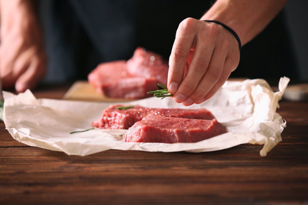 chef using butcher paper to wrap a piece of meat 