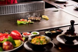chef grilling veggies and meat, teppanyaki vs hibachi