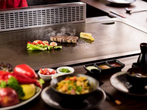 chef grilling veggies and meat, teppanyaki vs hibachi 