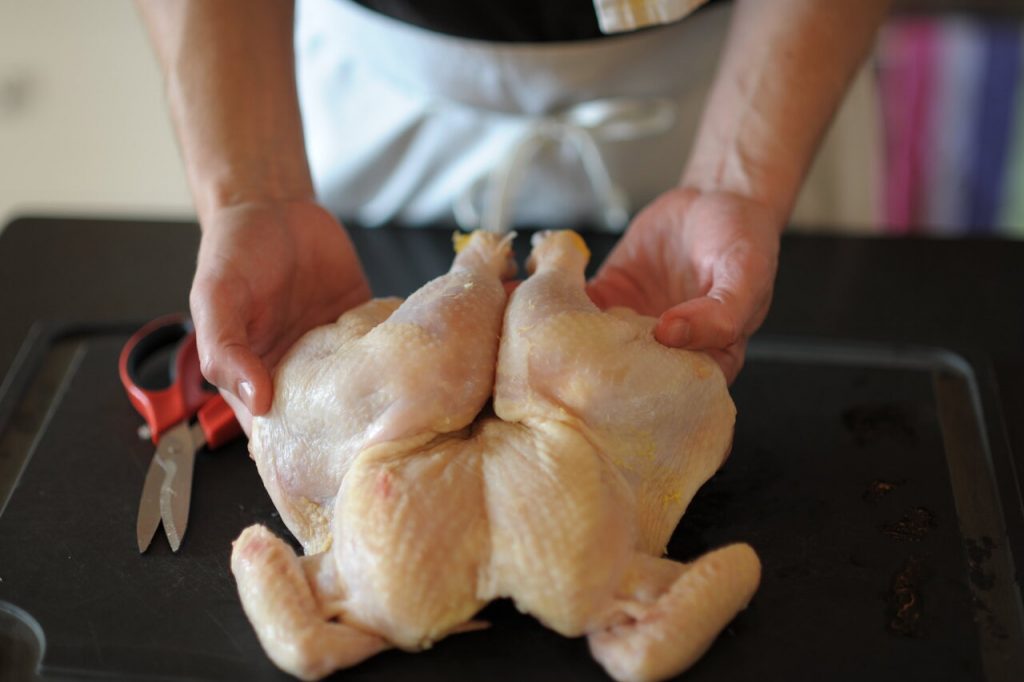 chef tucking the spatchcocked chicken's wing