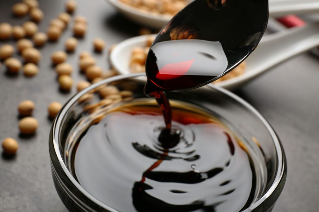 a close-up shot of pouring soy sauce in a glass bowl