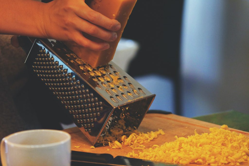 a person grating cheese using a box grater