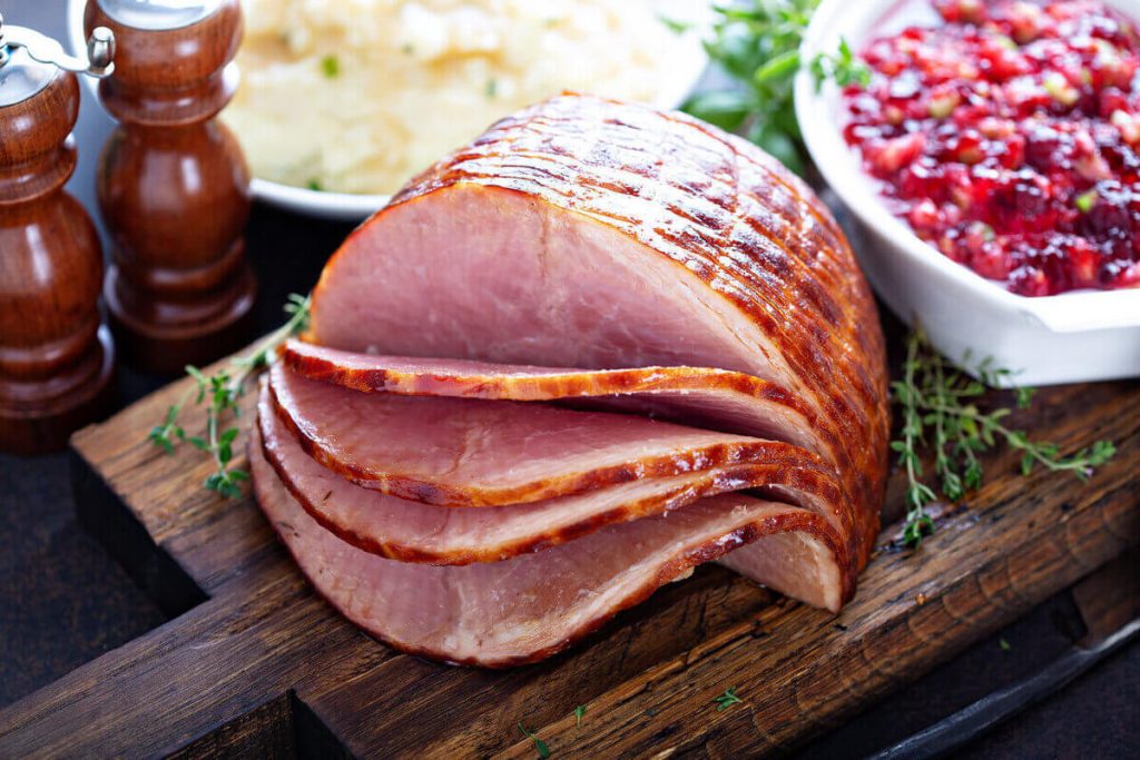 Holiday ham sitting on a wooden chopping board