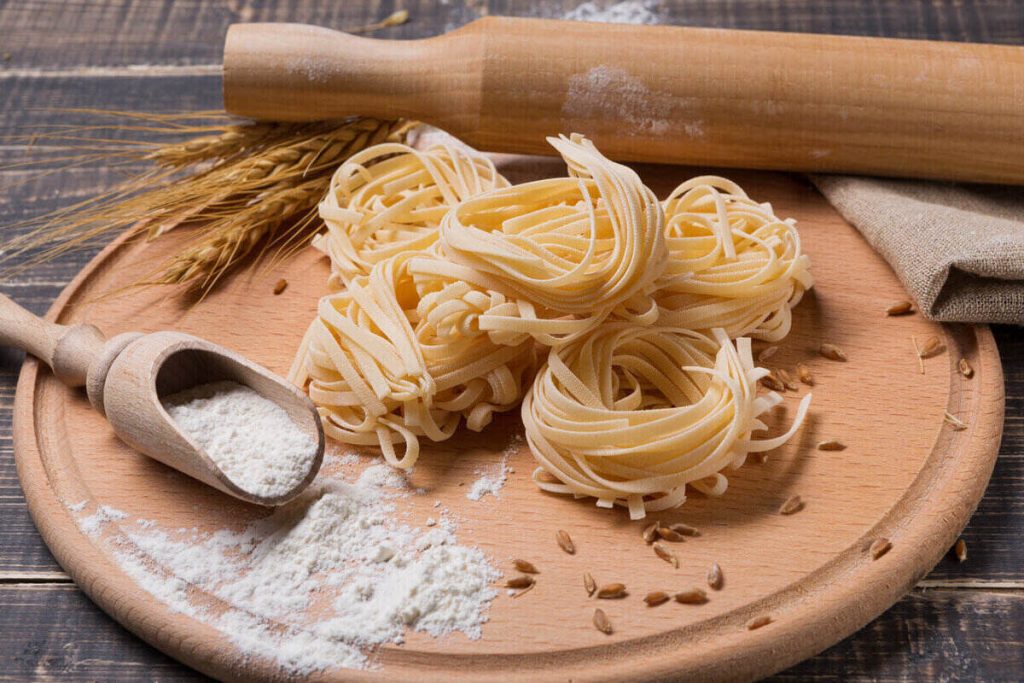 fettuccine noodles on wooden chopping board