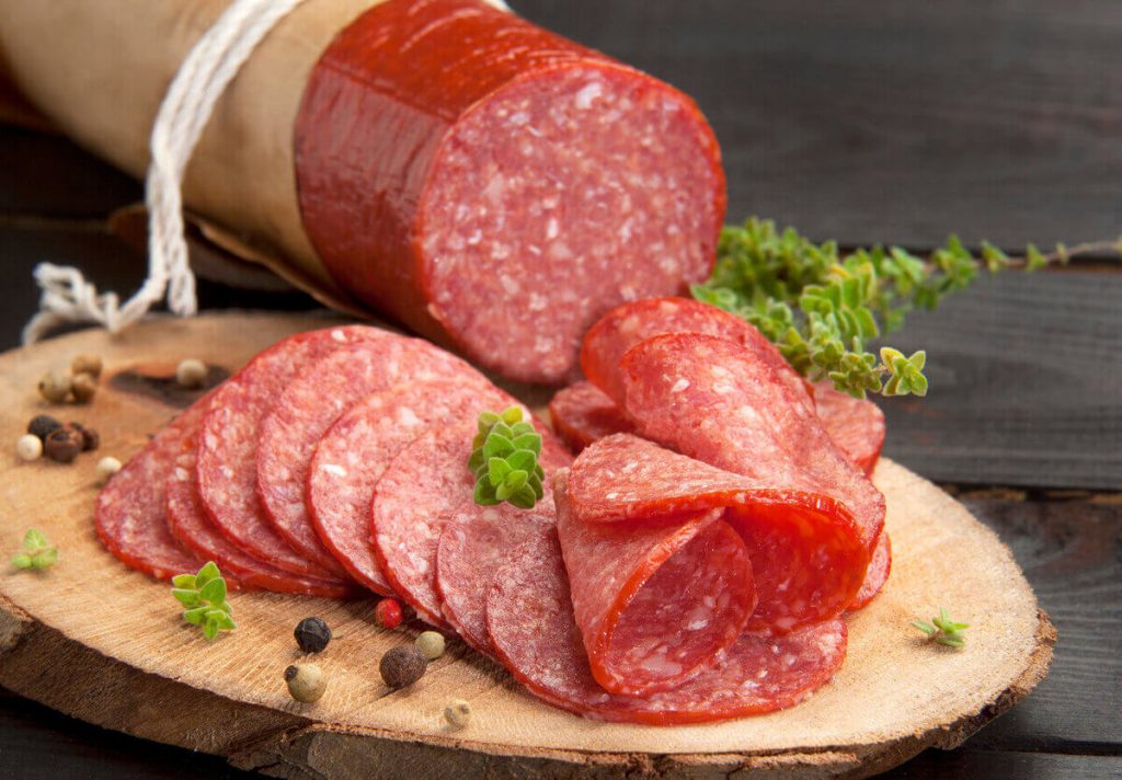 thinly cut salami slices on wooden chopping board