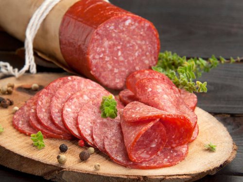 thinly cut salami slices on wooden chopping board