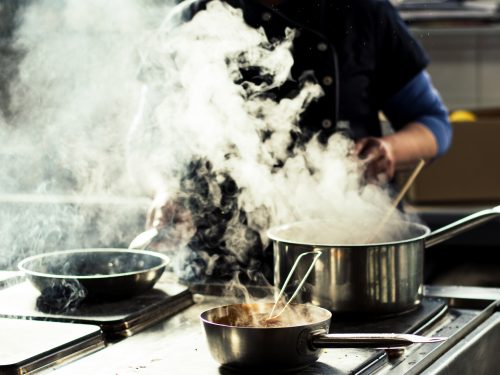 Chef cooking soup and water evaporating from a pot at a restaurant kitchen