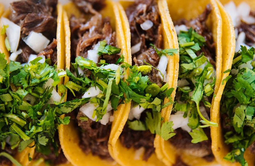 Sweet Pork Tacos Recipe - Tortillas stuffed with slow-cooked, shredded pork and topped with herbs and minced white onions.