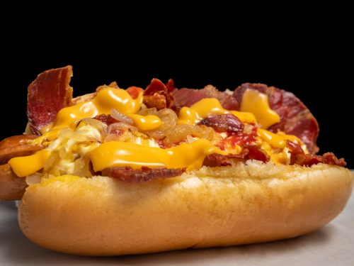Bacon-Wrapped Hot Dogs Recipe, delicious hot dogs in a bun wrapped in crispy bacon with cheese and toppings